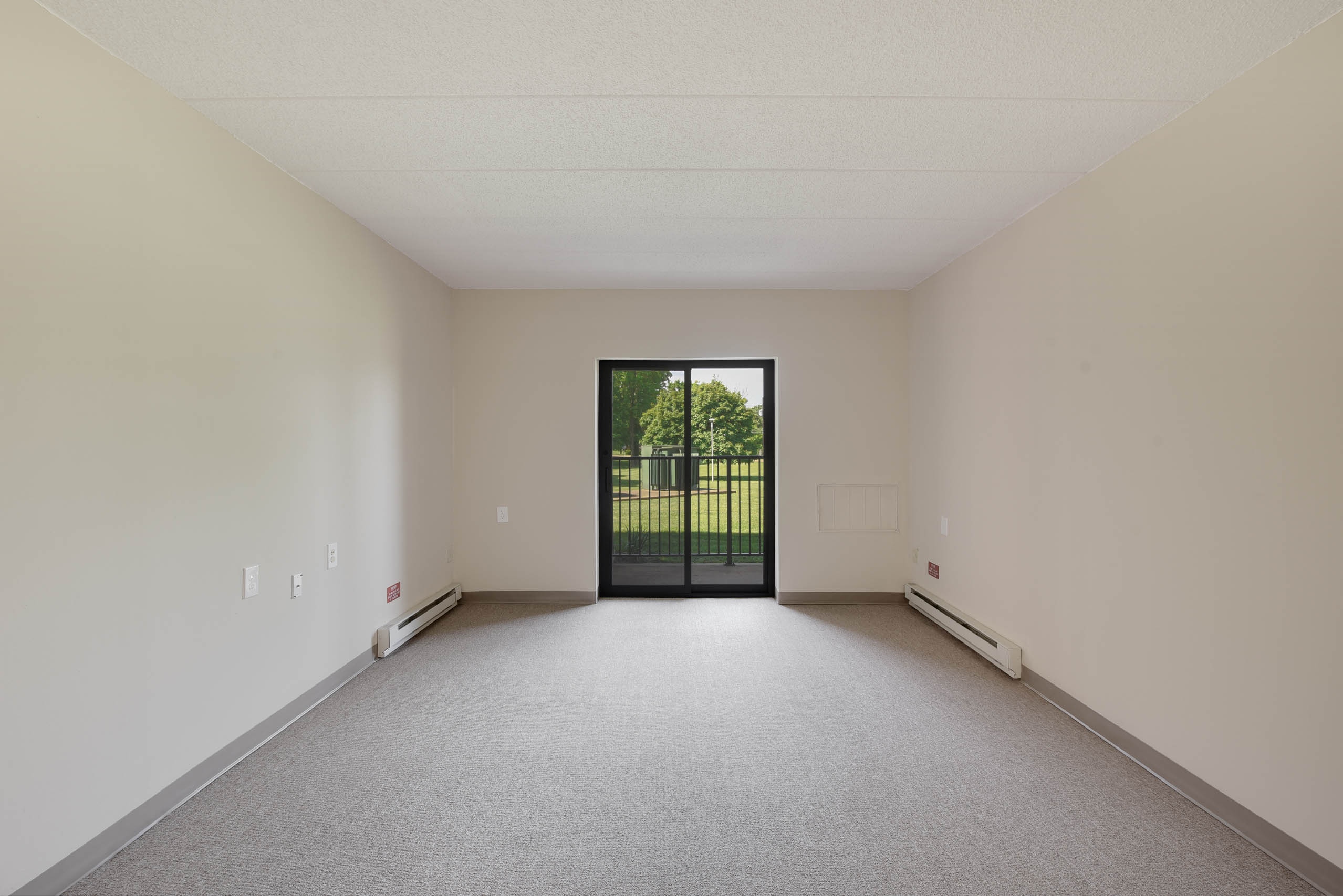 A room with a grey carpet and a black door.