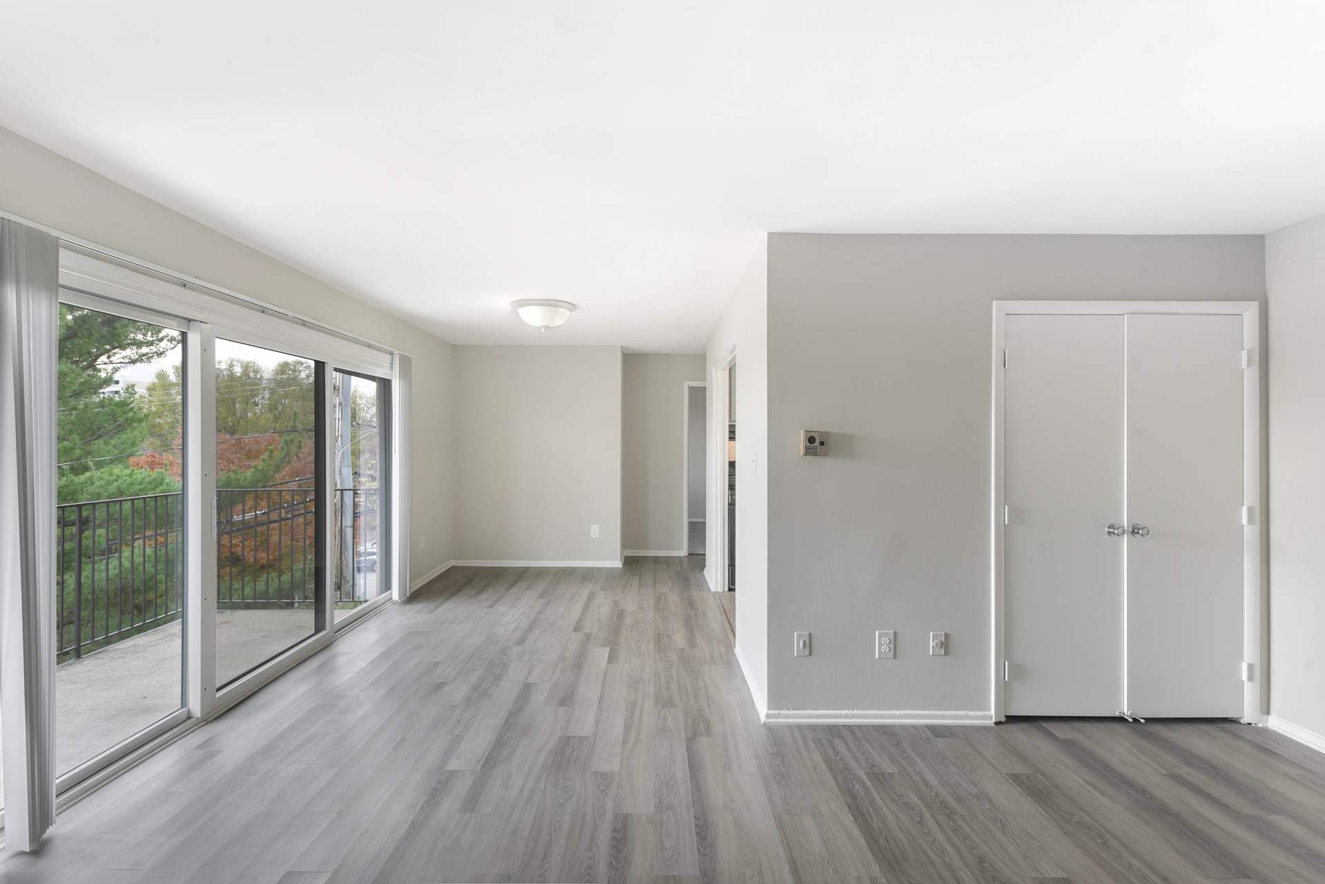 A room with a sliding glass door and wood flooring.