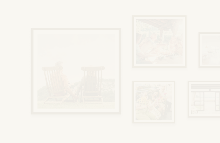 A gallery wall featuring framed photos of a couple holding hands while taking in a mountain view, a multigenerational family enjoying a meal outside together, and another family posing with flowers.