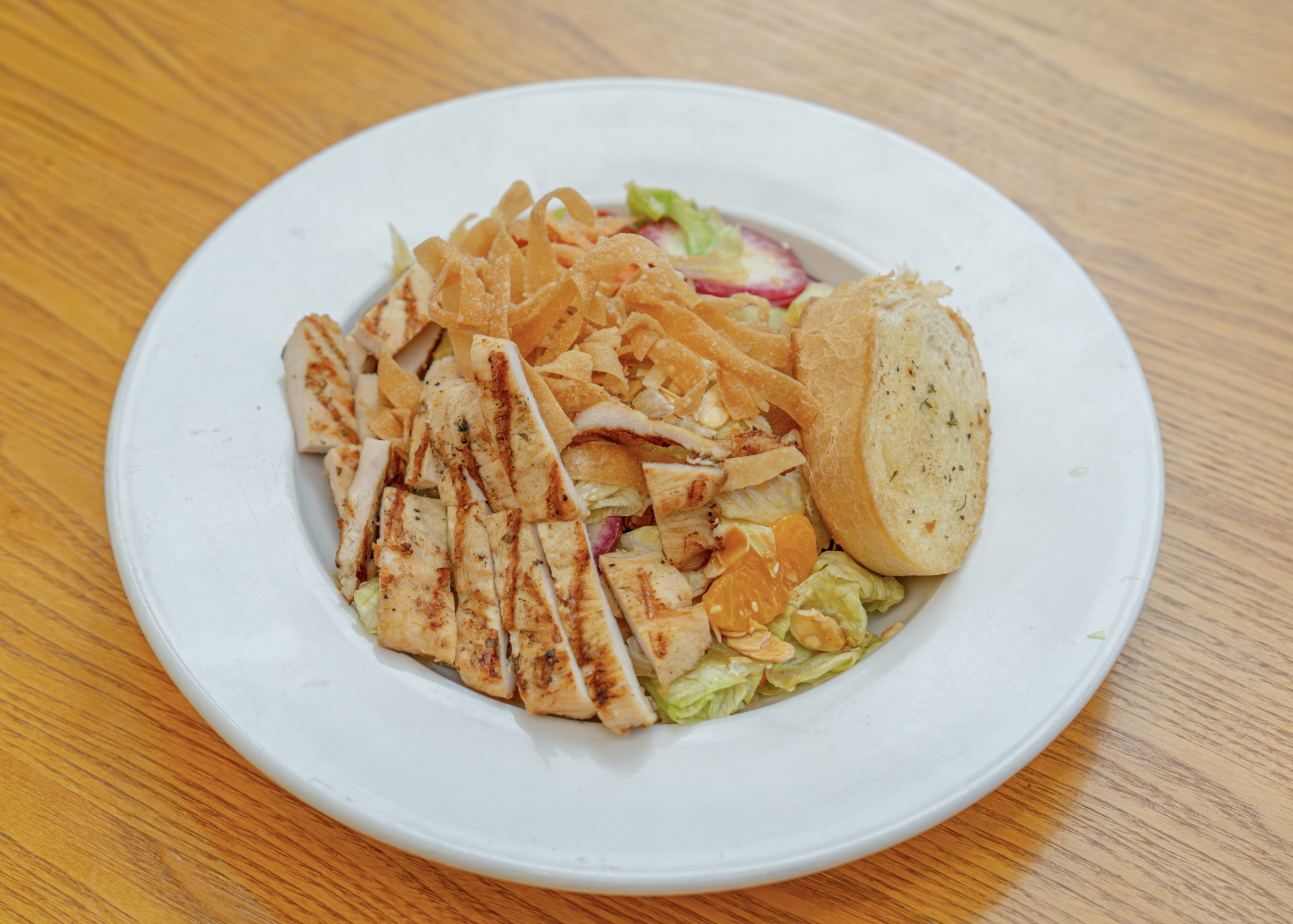 Fresh greens tossed in a cilantro Caesar dressing, topped with marinated chicken breast, cucumbers, tomatoes, avocado, crisp tortilla strips, served with garlic bread.