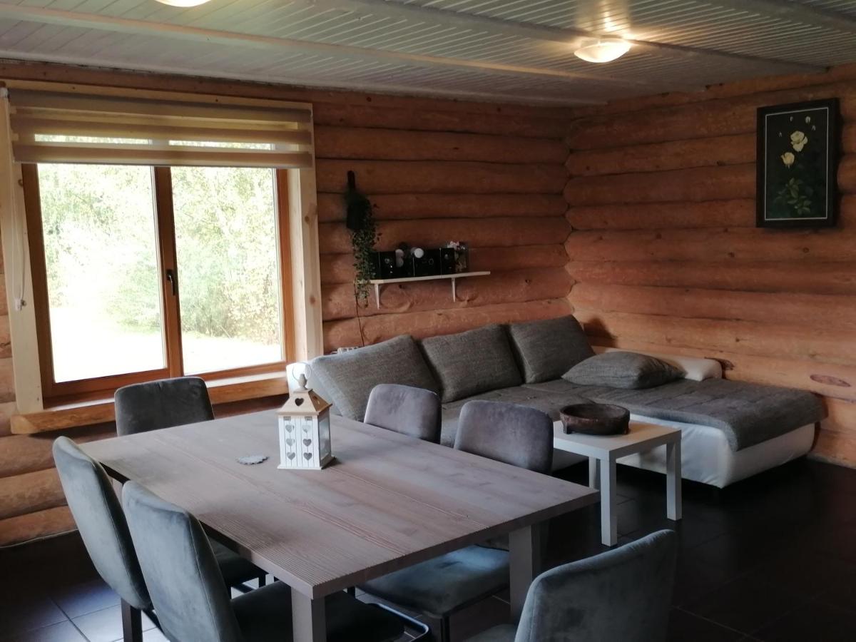 Gaiša un mājīga guļamistaba viesu namā 'Palmas' ar komfortablu gultu, koka detaļām un logu ar skatu uz dabu.