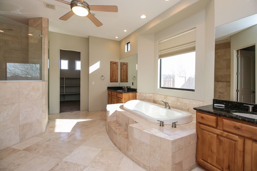 Master bathroom with dual sinks on either side of the tub along with a large shower and walk-in closet at Invitation Homes Phoenix.