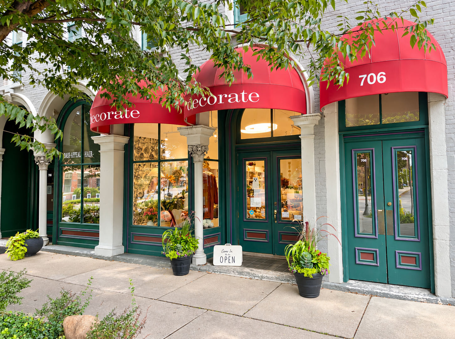 Decorate’s welcoming storefront features signature red awnings, elegant green doors, inviting window 