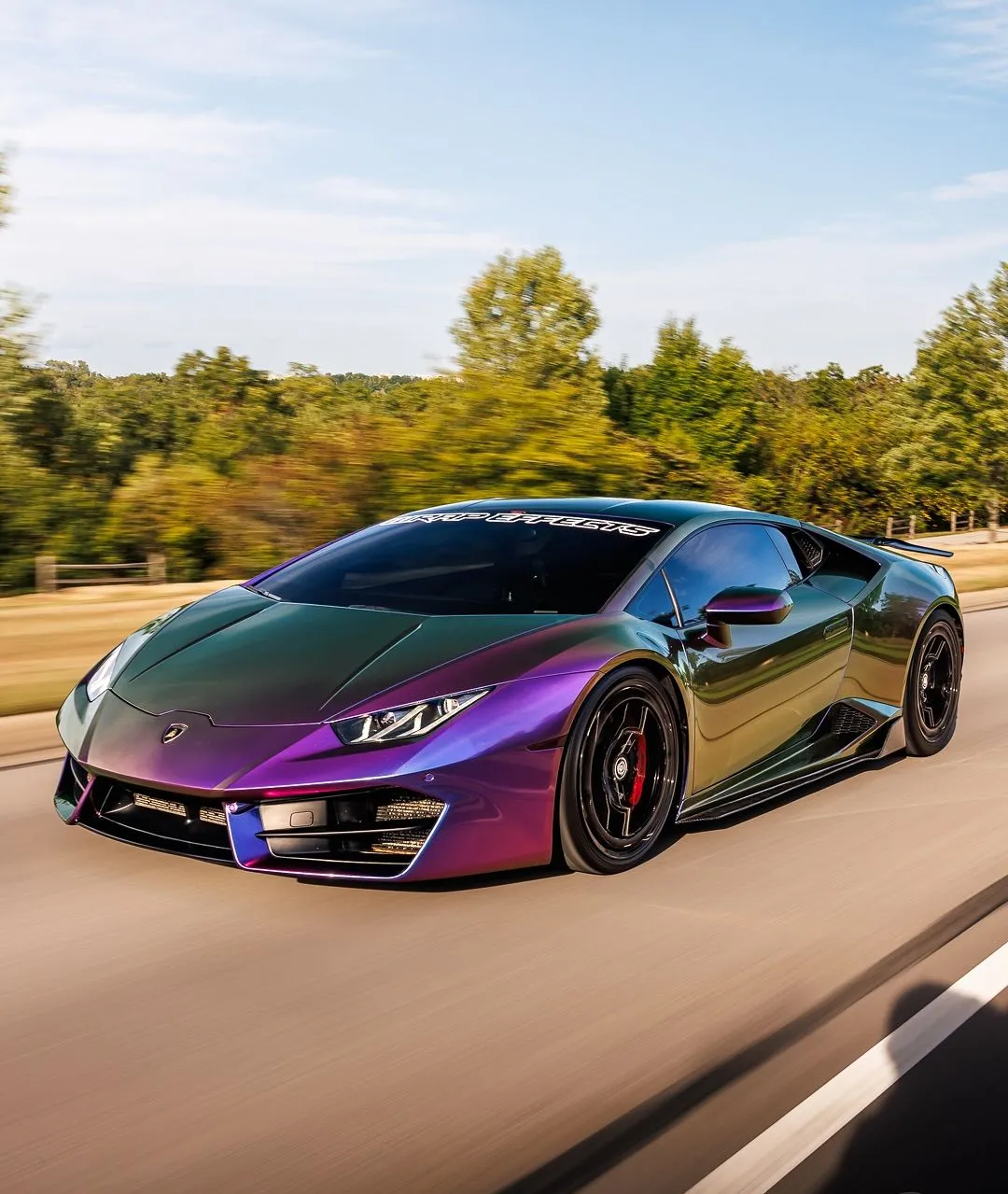 Lamborghini Huracán finished in dramatic purple and green color-shifting wrap driving at speed, highlighting exotic styling, aggressive aerodynamics, premium wheels, and flawless professional automotive wrap installation.