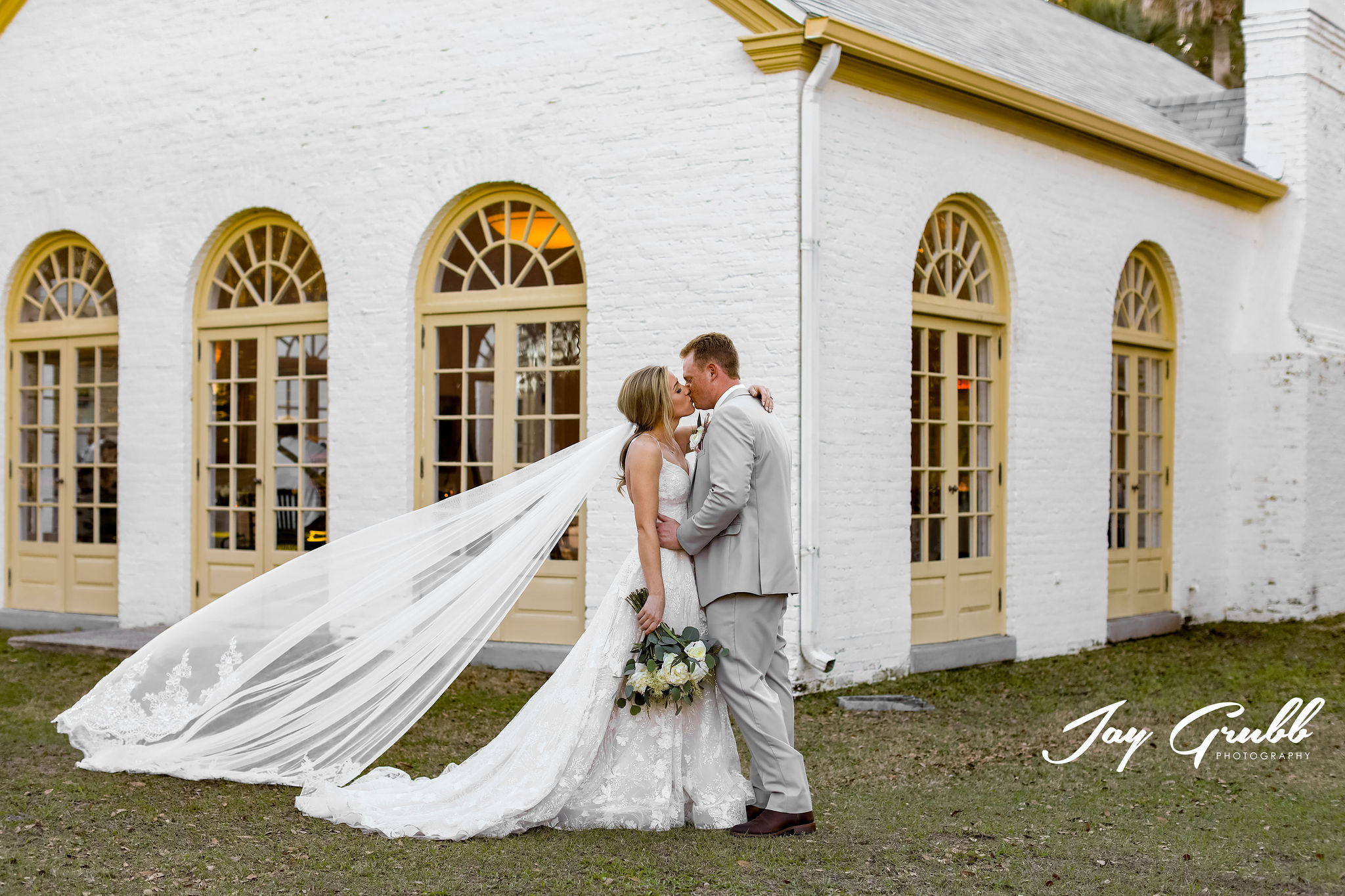 bride with long vail while holding groom at Ribault Club wedding venue 