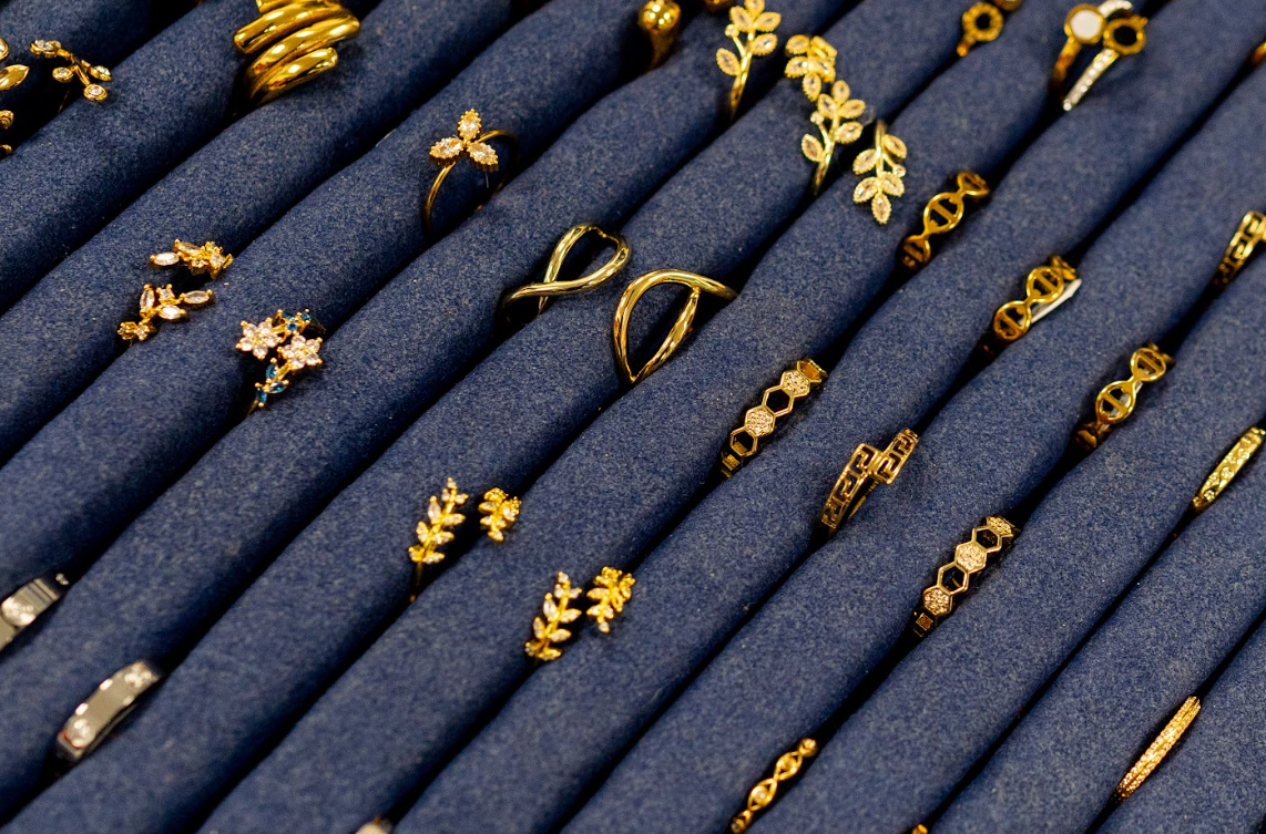 Explore gold-toned rings at Eliana Curated in Town Alexandria, VA. Floral, geometric, and open designs shine on a navy display, offering elegant accents for everyday styling and thoughtful gift ideas.
