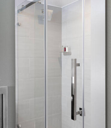 Sleek bathrooms offer a back-lit mirror and glass-enclosed shower.