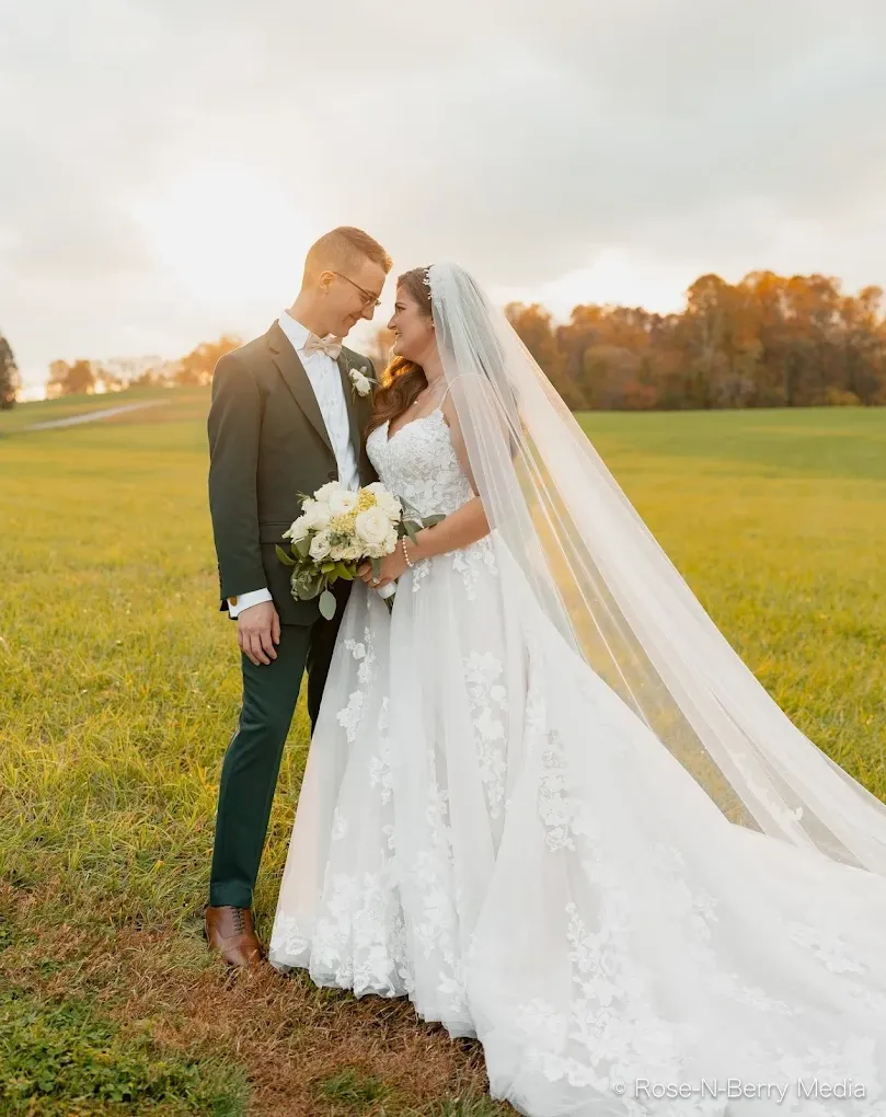 wedding photo of bride and groom in an open meadow closely looking at each other in slightly overcast weather.