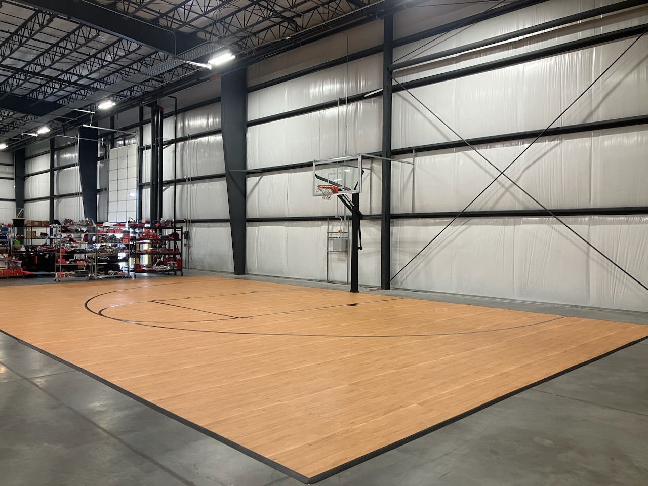 Indoor basketball half-court in a warehouse setting.
