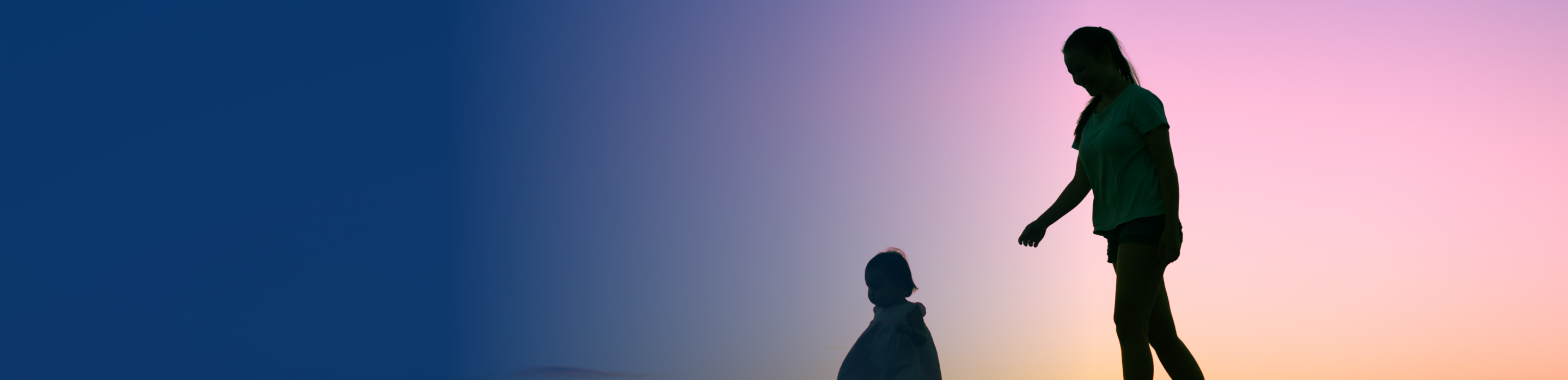 Silhouettes of a woman and baby out for a walk together at sunset.
