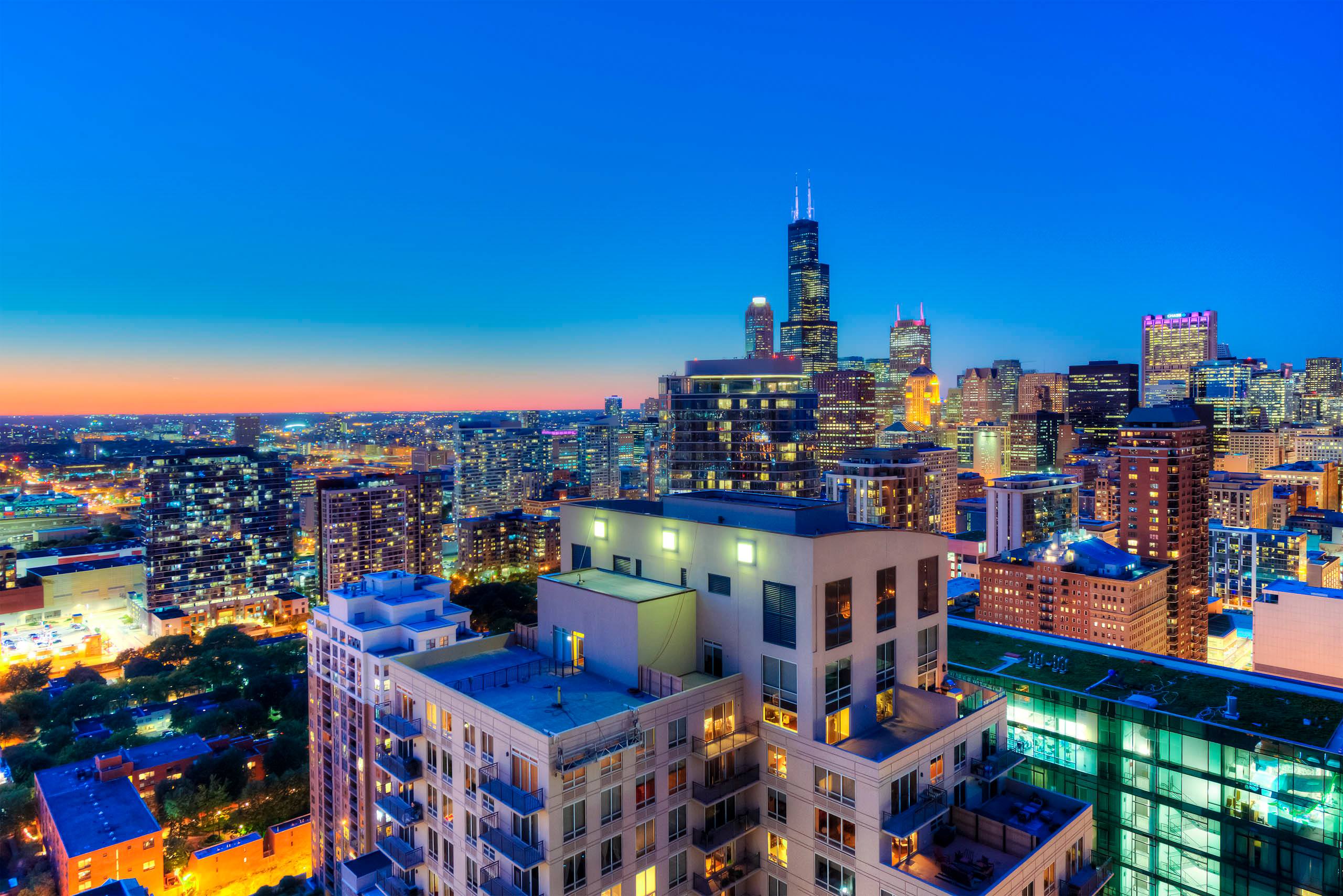 Aerial view of rooftop decks and downtown skyline at twilight 