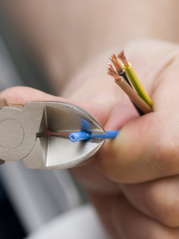 Copper wiring being trimmed with diagonal cutters during electrical installation work.