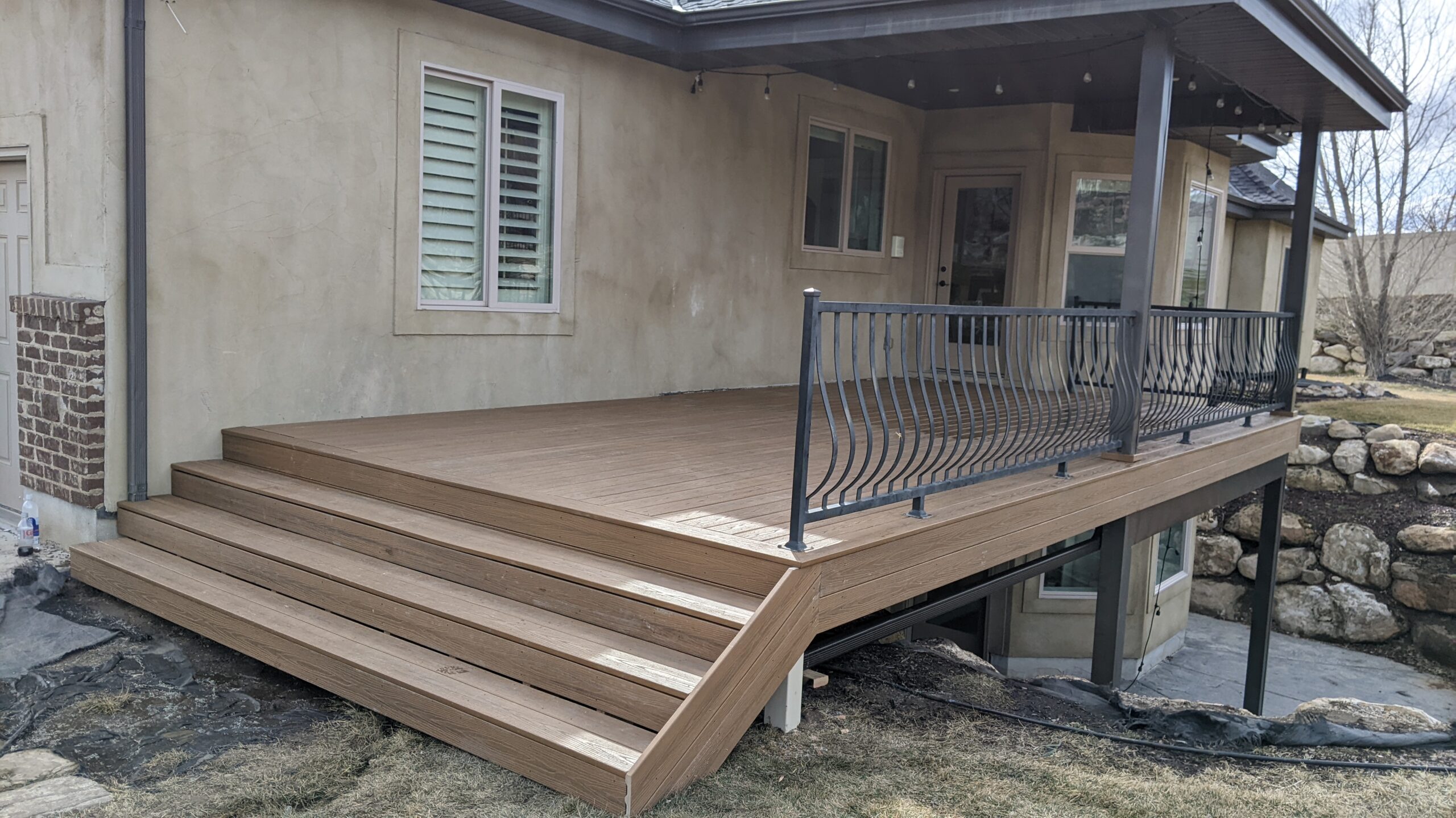 Extend your outdoor living possibilities with this custom deck by DeckPro LLC, which combines rustic elements with modern materials. We installed low-maintenance composite decking in a warm brown tone and paired it with a unique railing system that features natural wood posts and integrated wire mesh infill panels. For the ultimate in functional design, we included extensive built-in L-shaped bench seating, creating a cozy and inviting perimeter perfect for taking in scenic views.