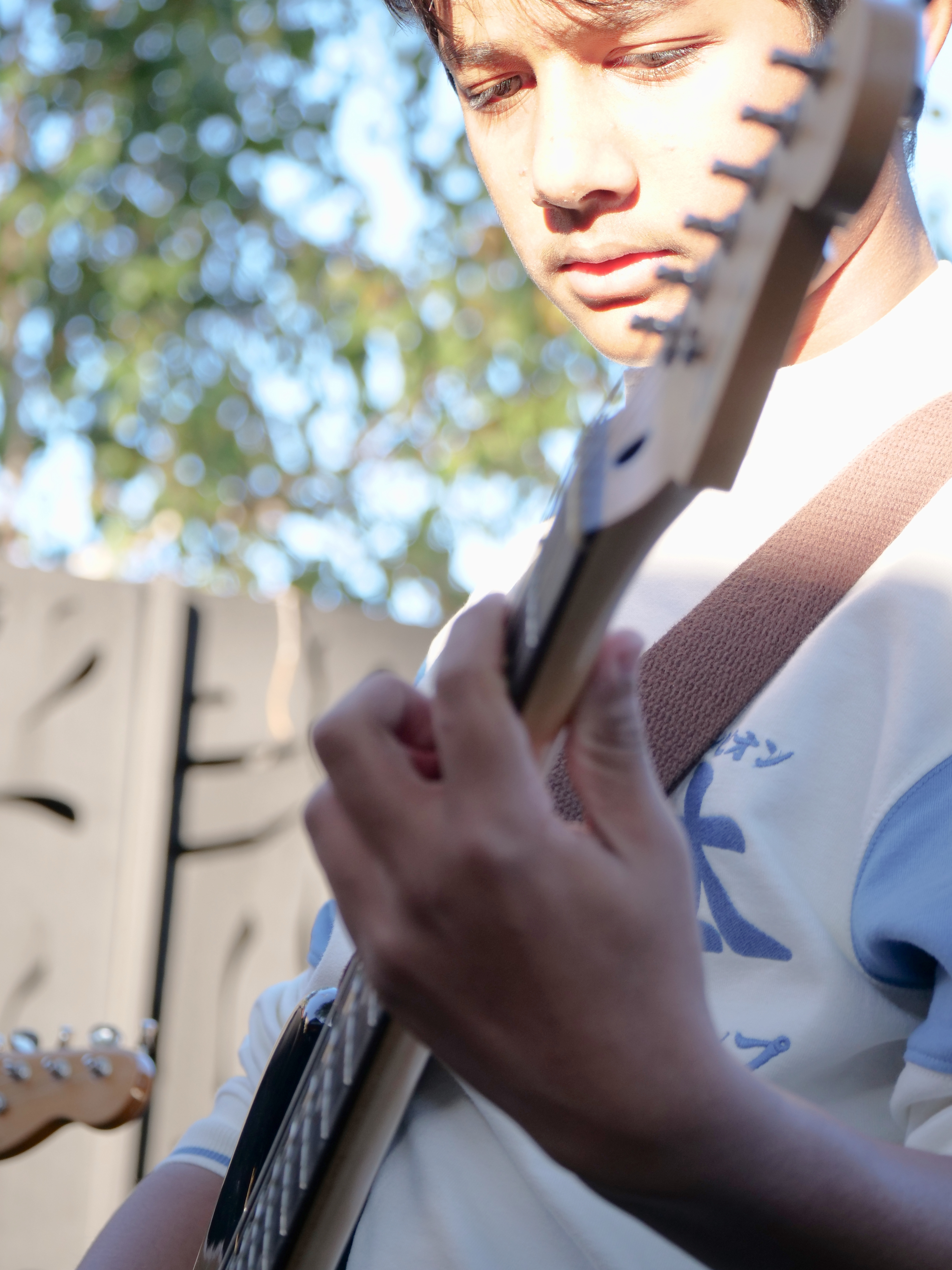 Student musician performing guitar outdoors, highlighting live performance training and youth music development.