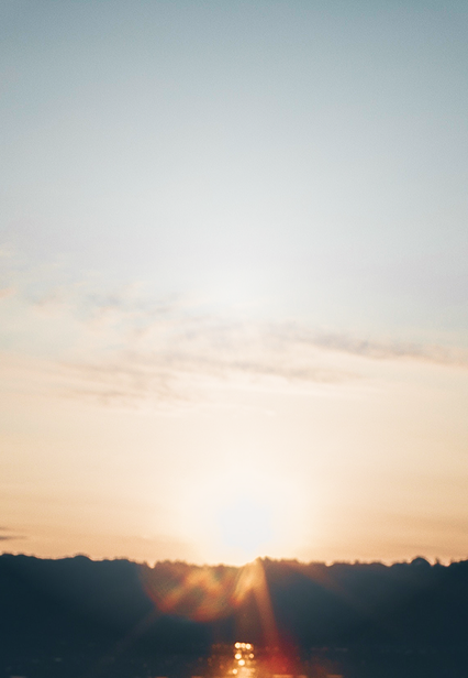Sun setting over a silhouetted forest surrounding a lake.