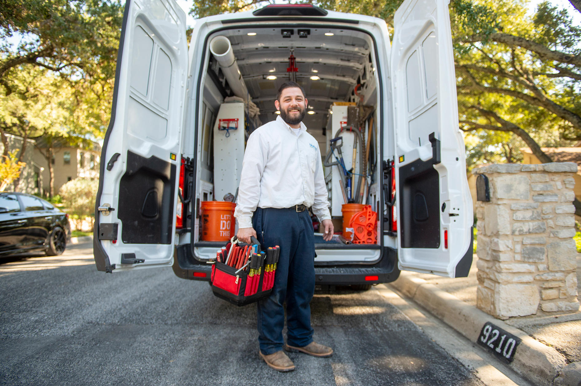 Plumber standing behind of a service van ready for a water and sewer line cleaning, repair, and replacements job in the St Tammany Parish, LA area.