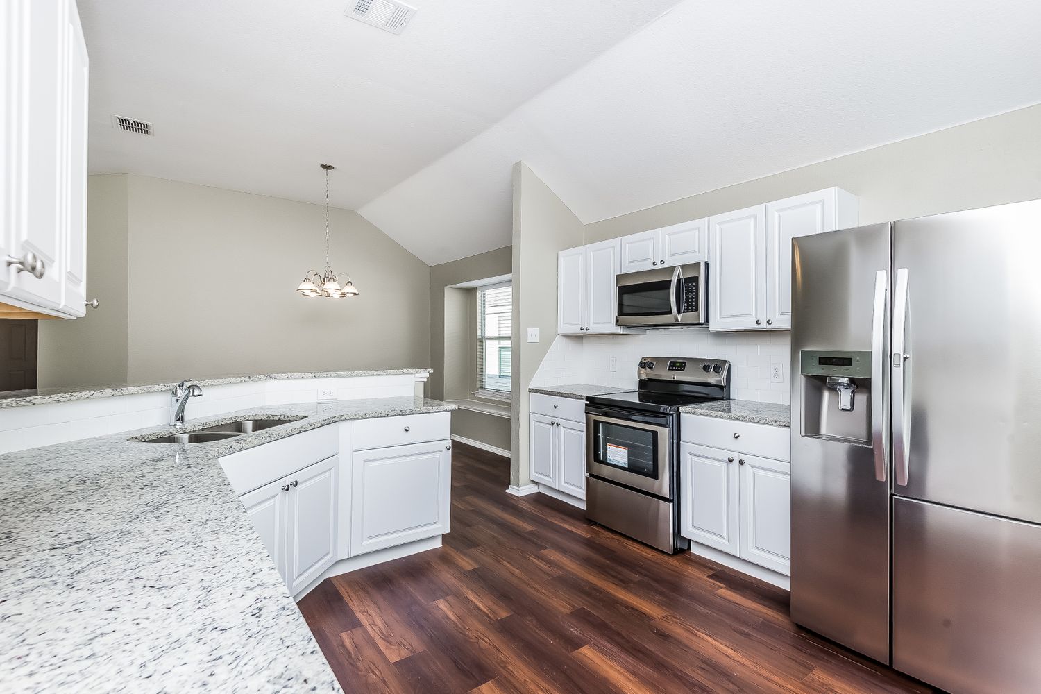 Modern kitchen with white cabinets, stainless-steel appliances, and granite countertops at Invitation Homes Dallas.