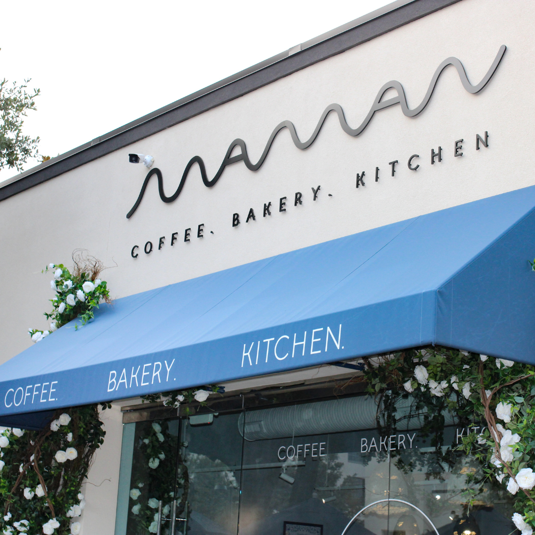The exterior of maman Park Cities features signature blue awnings, climbing white florals, and outdo 