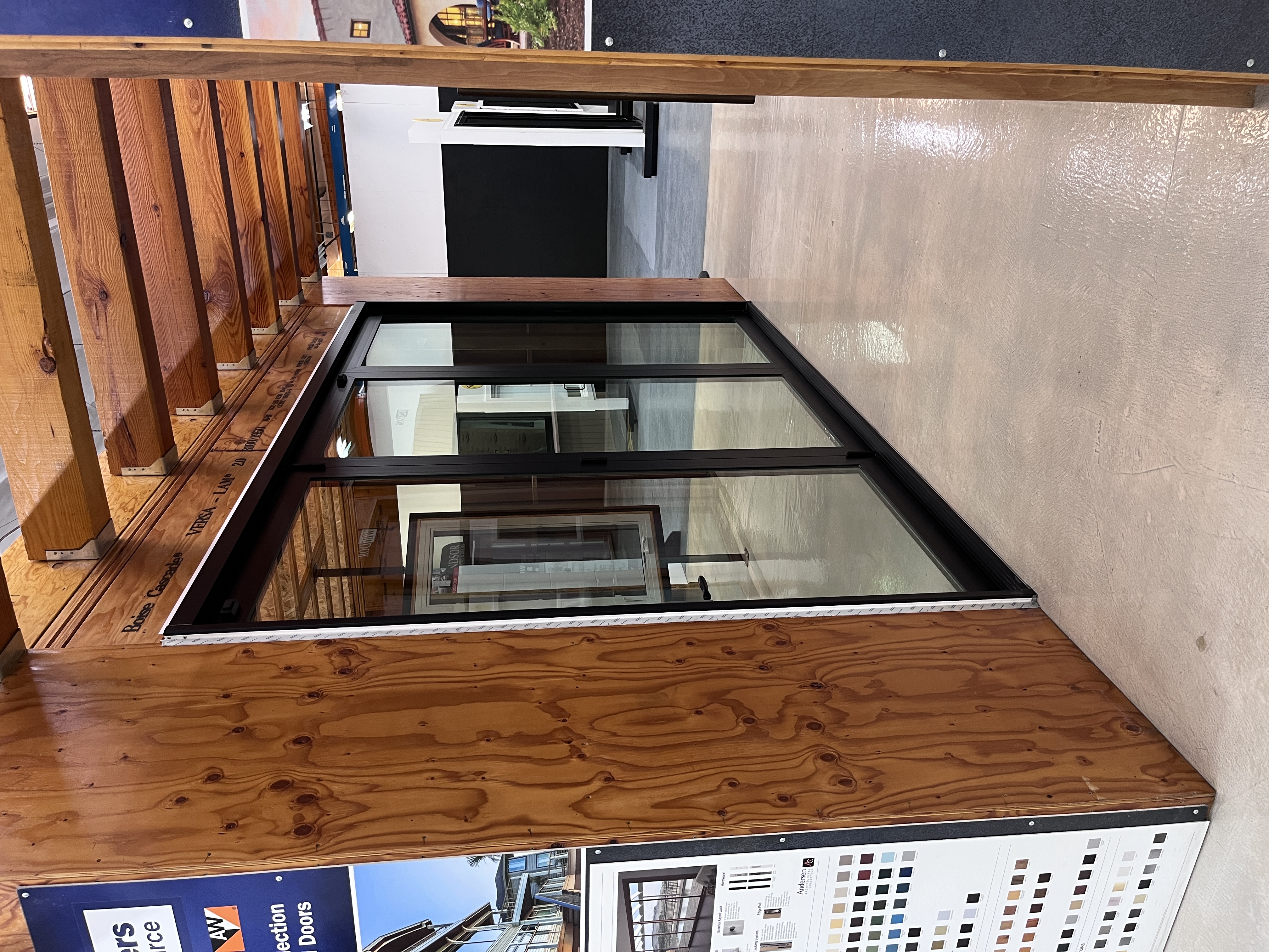 Sliding glass door showroom display at Builders FirstSource Thousand Oaks, CA, with window and door brand signage and hardware color samples visible nearby.