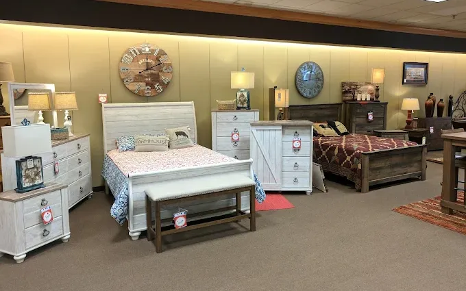 Bedroom furniture display at Neill&rsquo;s Homestore showcasing bed frames, dressers, nightstands, lamps, wall clocks, and coordinated d&eacute;cor in a styled showroom setting.