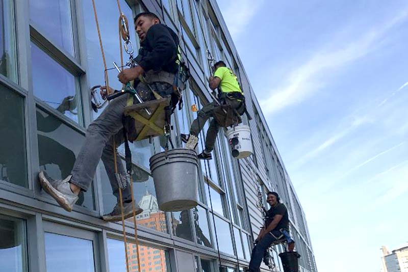 Snugs Services technicians performing professional high-rise window and exterior cleaning on a comme 
