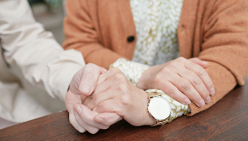 Close-up of two people holding hands.