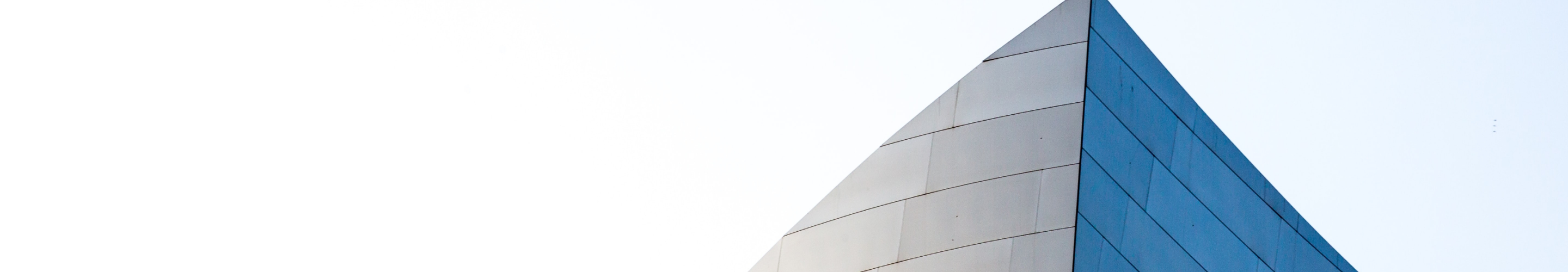 Pointed tip of a glass-faced skyscraper against a clear sky.
