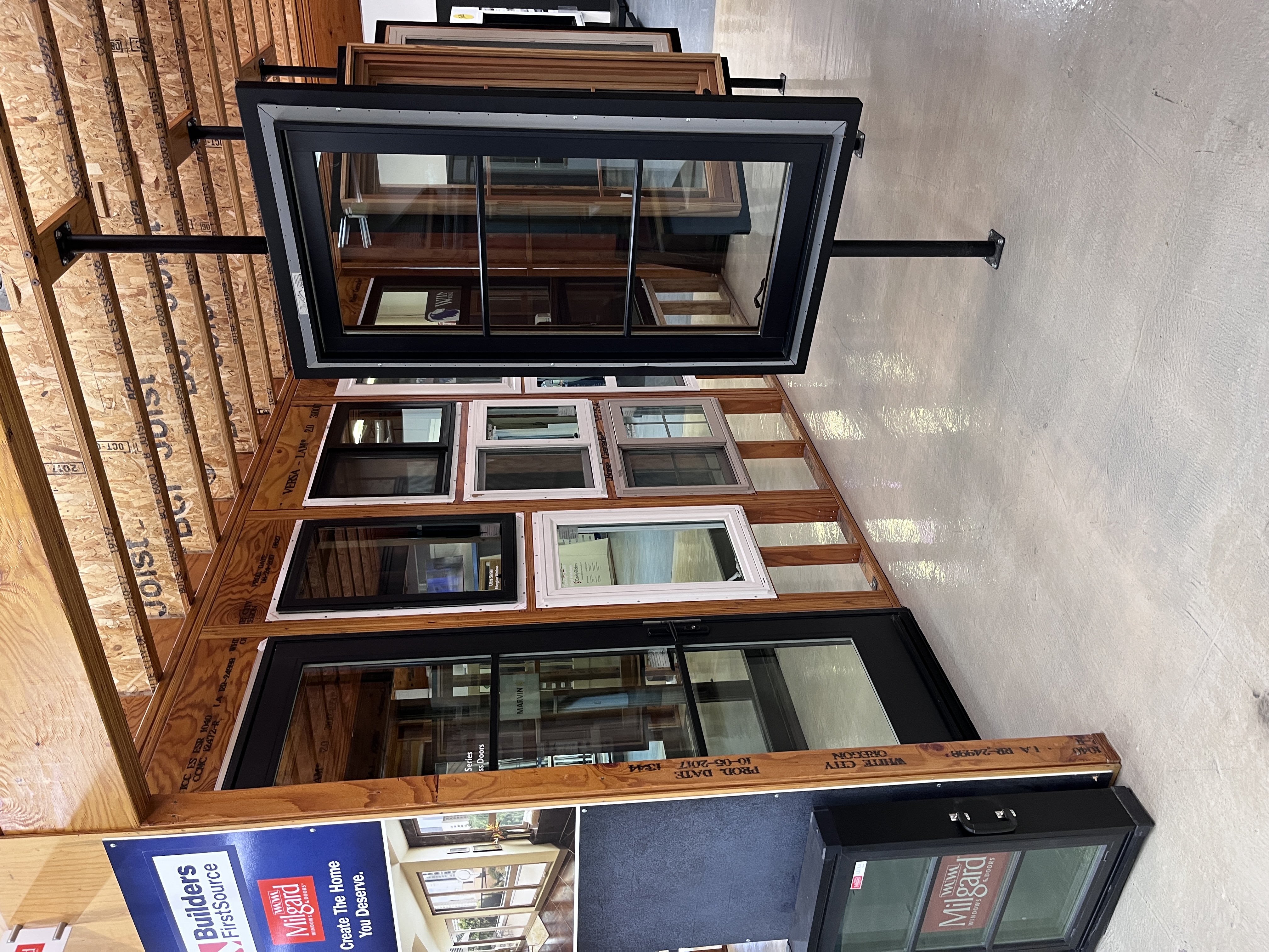 Milgard window and door showroom display at Builders FirstSource Thousand Oaks, CA, featuring a swinging glass door and a rotating window sample mount.