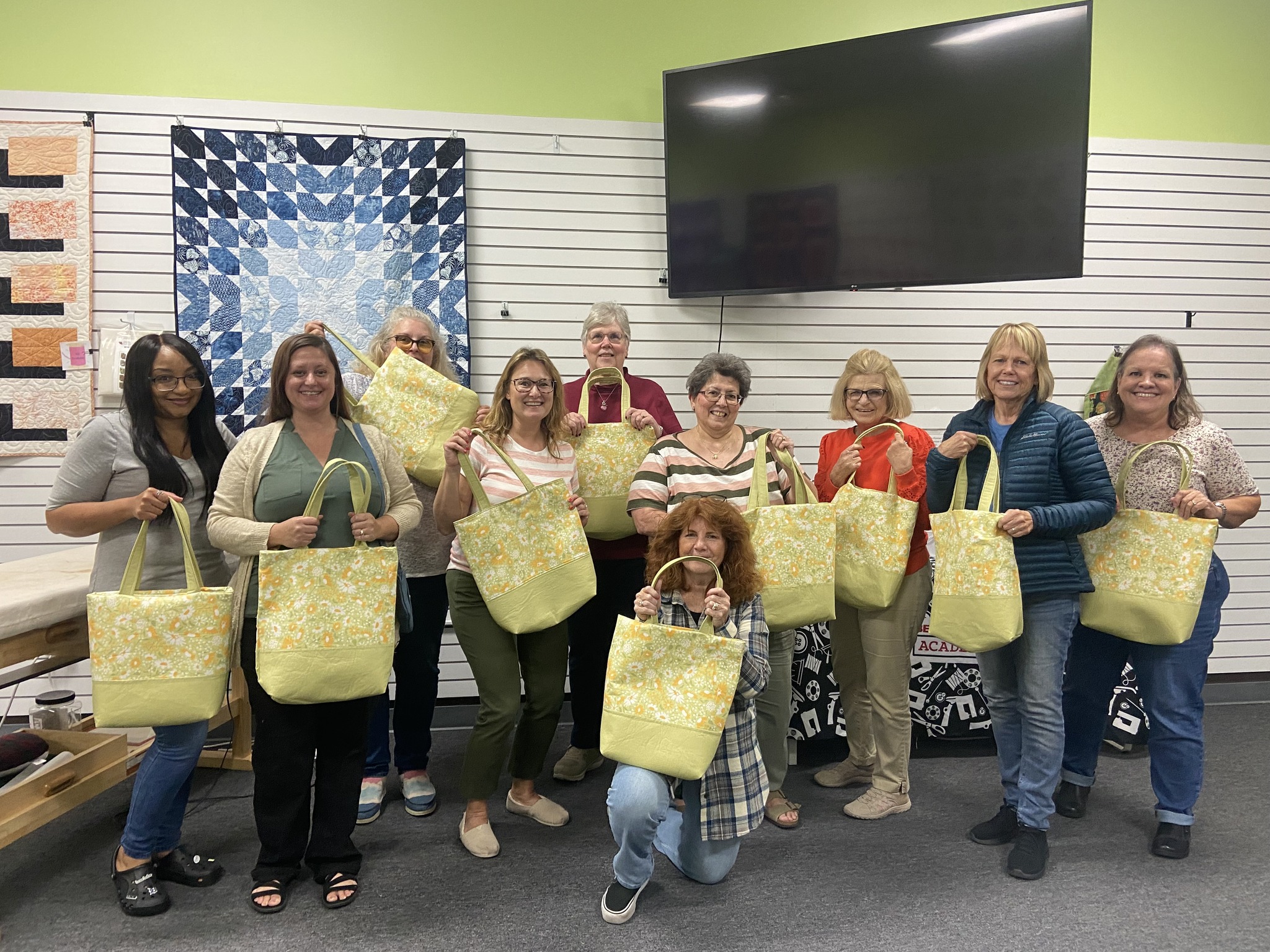 Students proudly showcase their finished custom throw pillows after a Decorative Stitch class. This hands-on sewing workshop featured decorative stitching, piping, construction techniques, and personalized home décor projects.