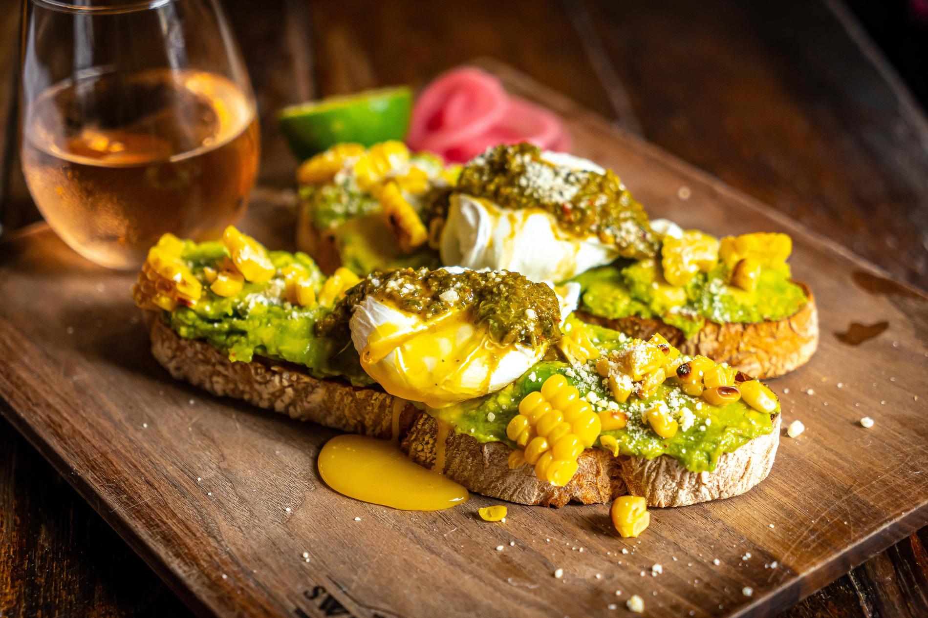 Avocado toast (brunch) with roasted corn, cotija, chimichurri and poached eggs