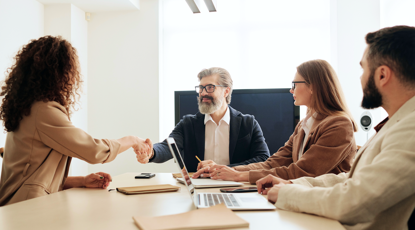 A client shaking hands with an external advisor during a meeting.