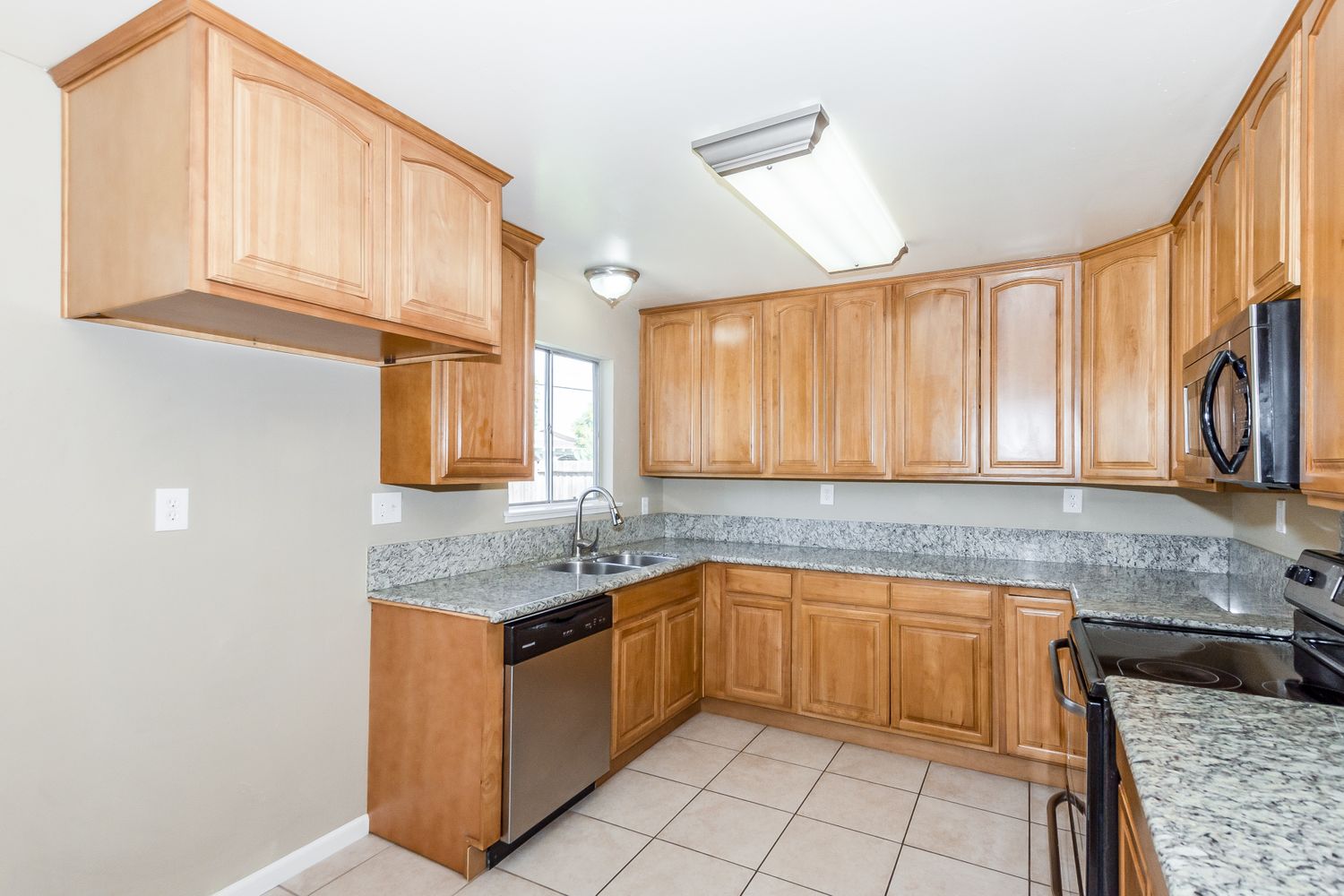 Kitchen with granite countertops, rich wood cabinets, and easy to care for tile at Invitation Homes Northern CA.