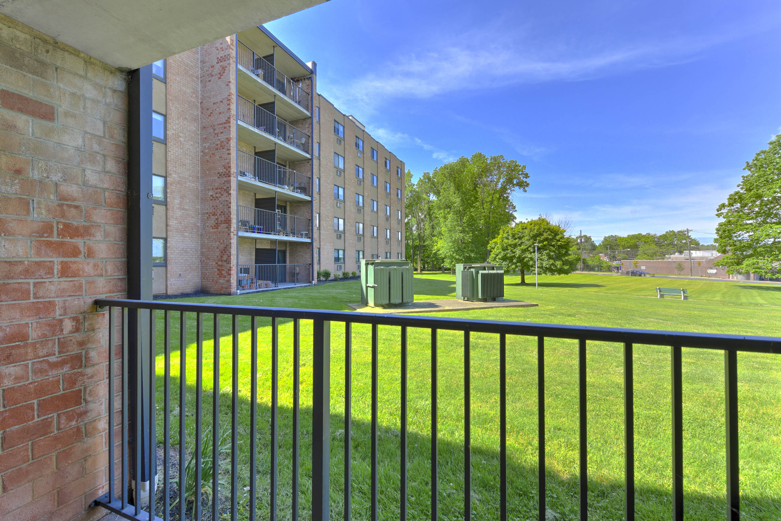 A balcony with a black railing overlooks a grassy area.