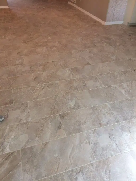Completed beige large-format tile flooring with a staggered installation pattern. 
