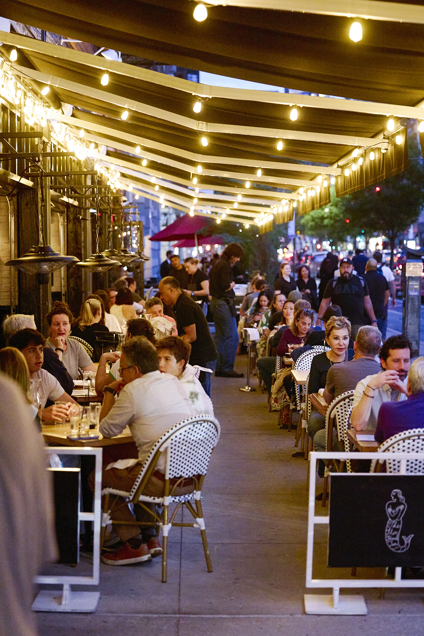 Guests enjoy outdoor dining at The Mermaid Inn, a neighborhood seafood restaurant known for fresh oysters, coastal-inspired dishes, handcrafted cocktails, and a welcoming atmosphere in New York City.