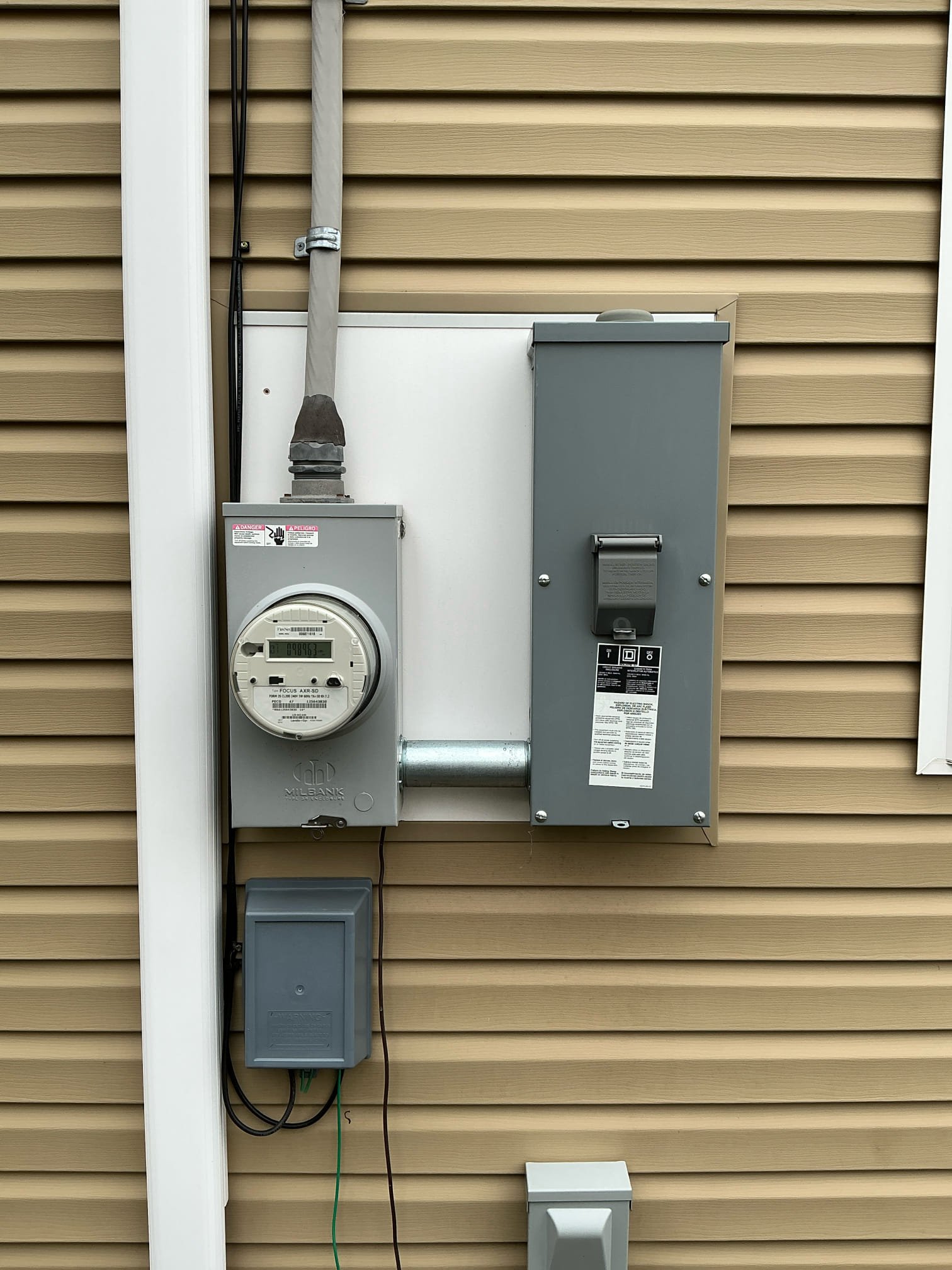 A Milbank meter base paired with a Square D main disconnect panel installed by Thomas Edison Electric on the exterior of a North Wales, PA home. The setup includes the utility meter, main breaker disconnect, and a small subpanel below for outdoor circuits.