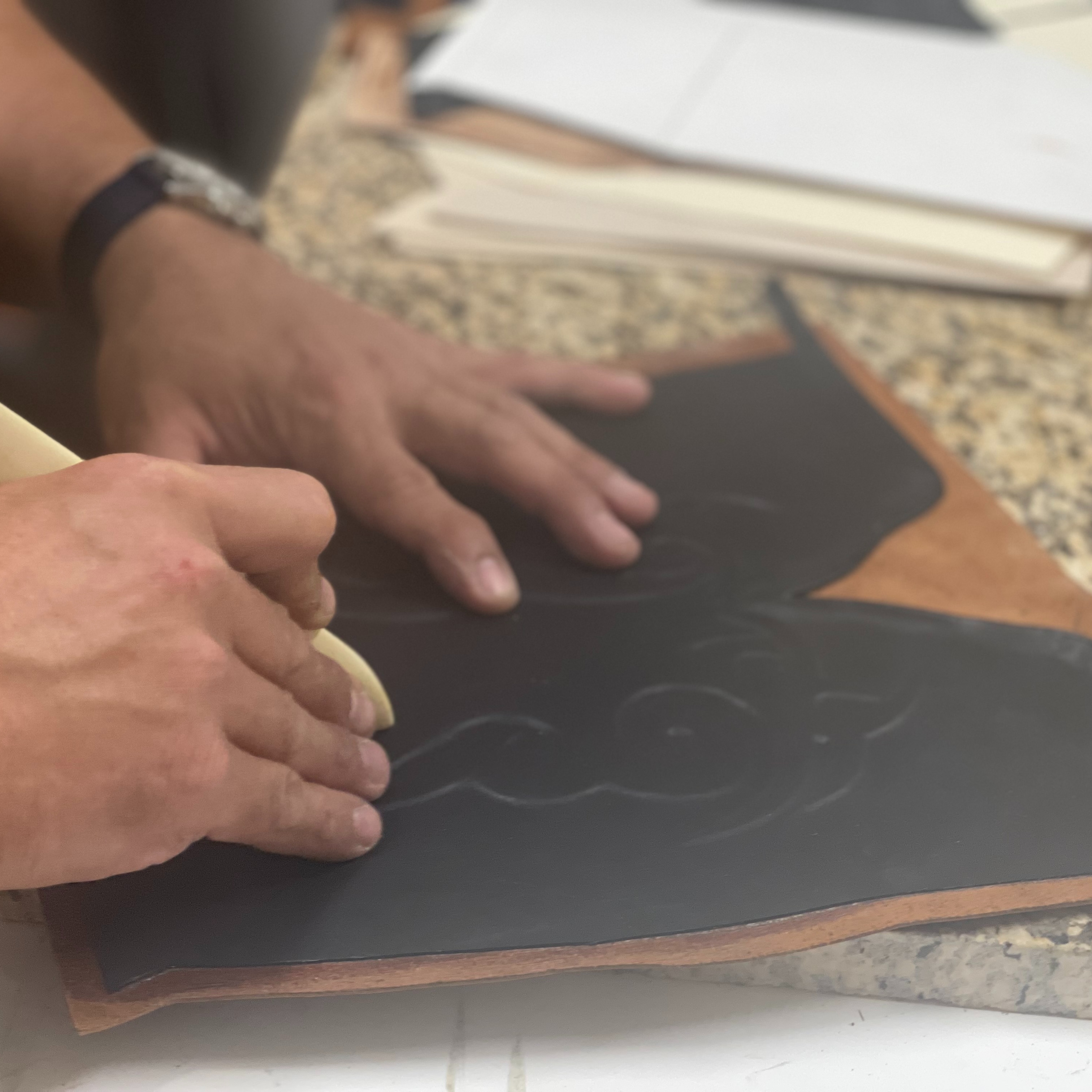 A bootmaker draws a custom design onto leather during the cowboy boot creation process. 