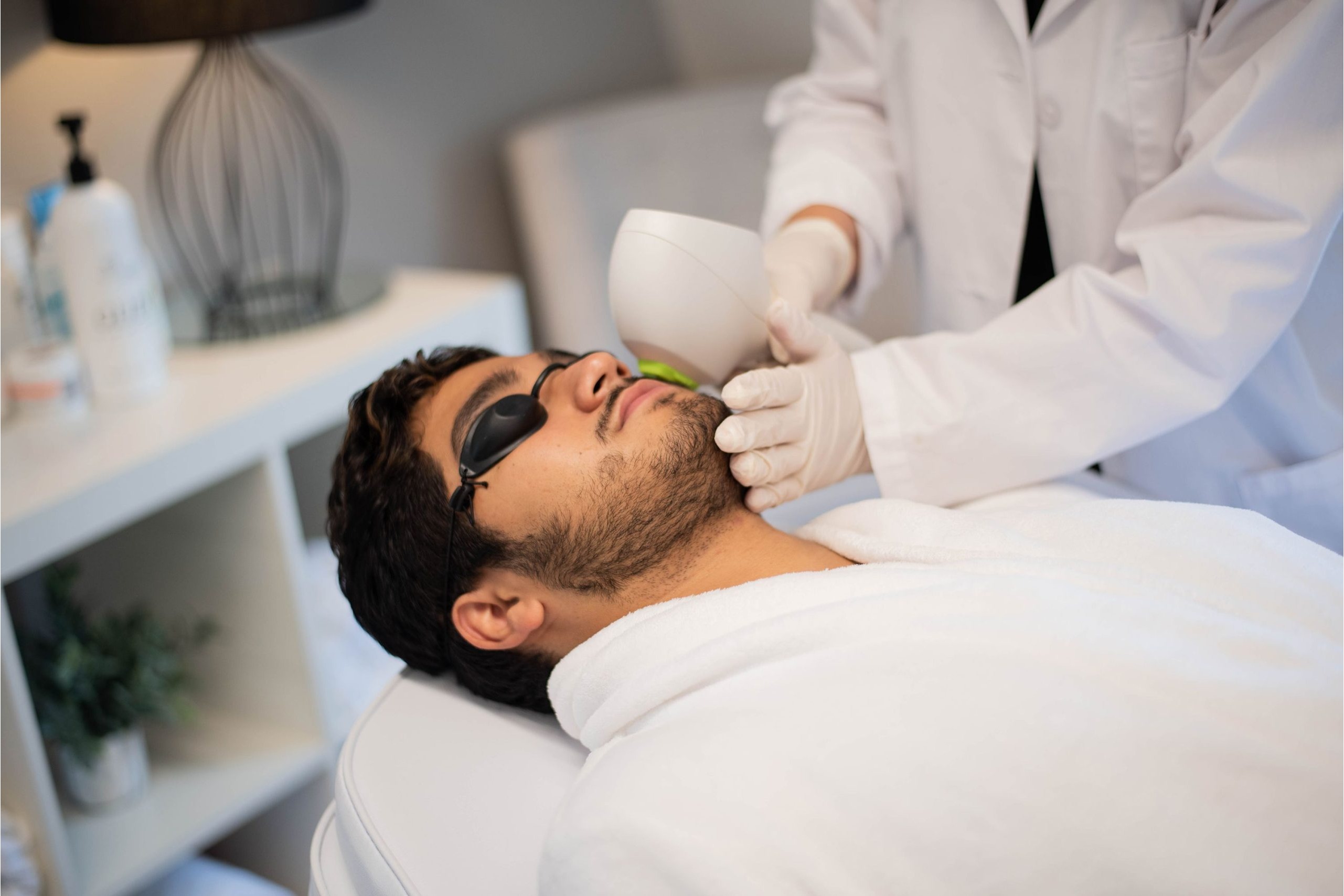 This image showcases a professional laser hair removal treatment for men at The Weight Loss & Skin Center. A trained medical aesthetic provider performs a non-invasive laser procedure on a male client’s facial area using advanced FDA-cleared laser technology. The client wears protective eyewear to ensure safety and comfort during the session. This treatment is designed to permanently reduce unwanted facial and body hair with precision and minimal discomfort. The calm, clinical environment reflects The WLS's commitment to safe, effective, and medically supervised aesthetic services in Alexandria, Virginia.