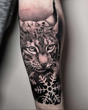 Eisenherz Tattoo und Piercing Magdeburg - Realistisches Luchs Tattoo in Black and Grey mit Schneeflocke und kontrastreichen Fellstrukturen. Starkes Tiermotiv für Suchbegriffe wie Luchs Tattoo, Tier Tattoo, Realistic Tattoo, Black and Grey Tattoo und...