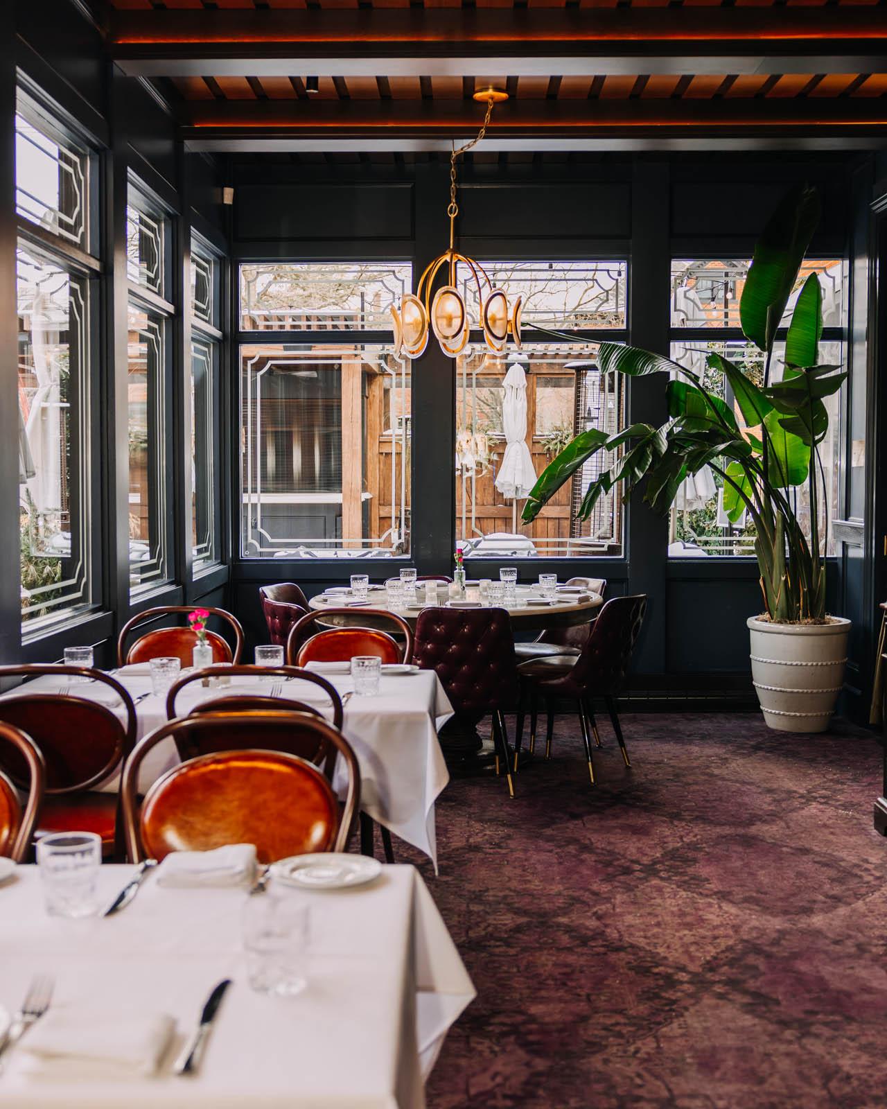 Window seating with tables for four and a large round table for 6 inside Cento