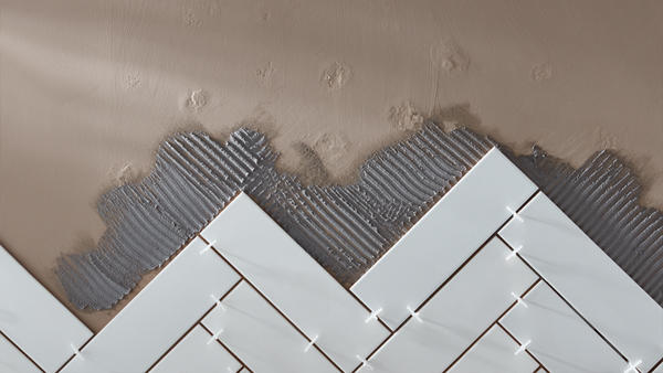 Metro tiles in a herringbone pattern on a wall with spacers and some tile adhesive