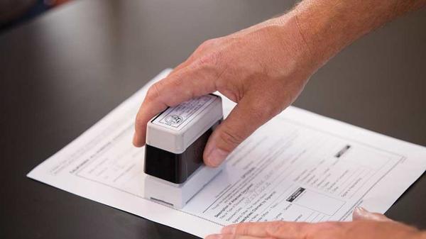 Hand with notary stamp notarizing a document