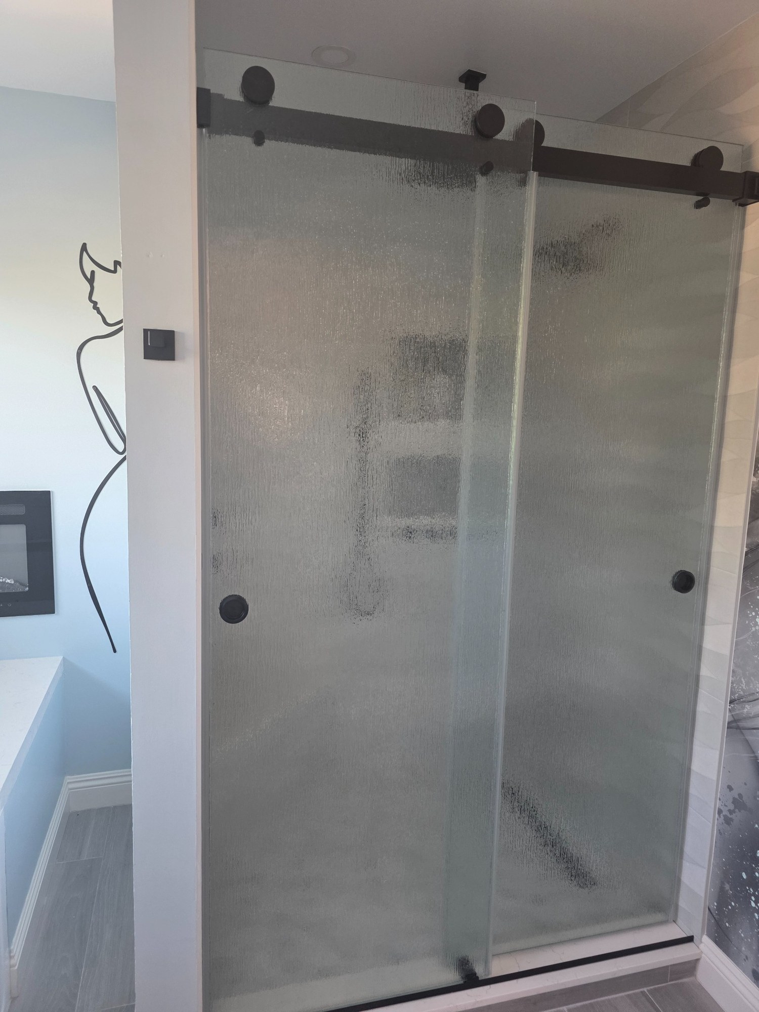 Glass-enclosed walk-in shower with modern hardware and tiled walls. 
