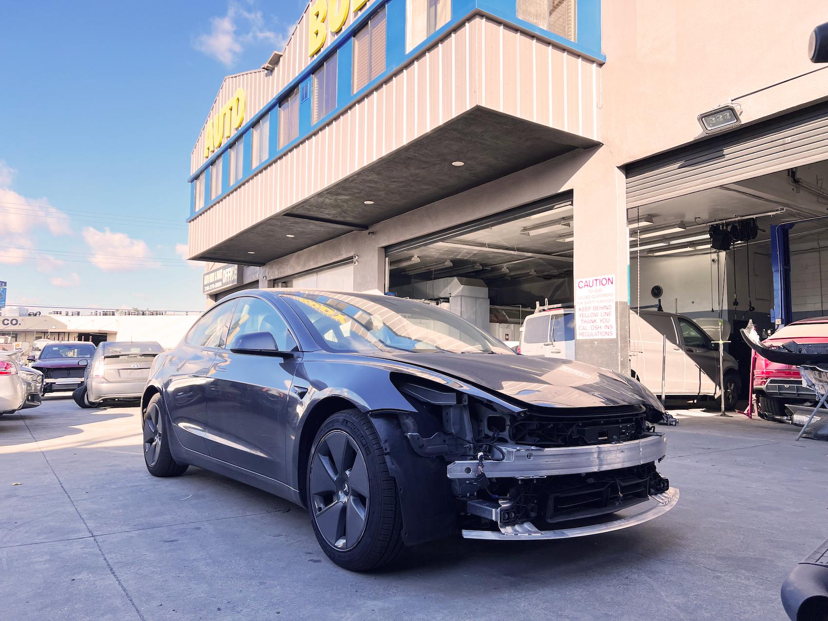 Detailed photo of Tesla Model 3 waiting at auto body shop parking lot for collision repair