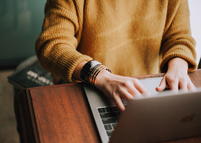 Close-up of an individual typing on their laptop.