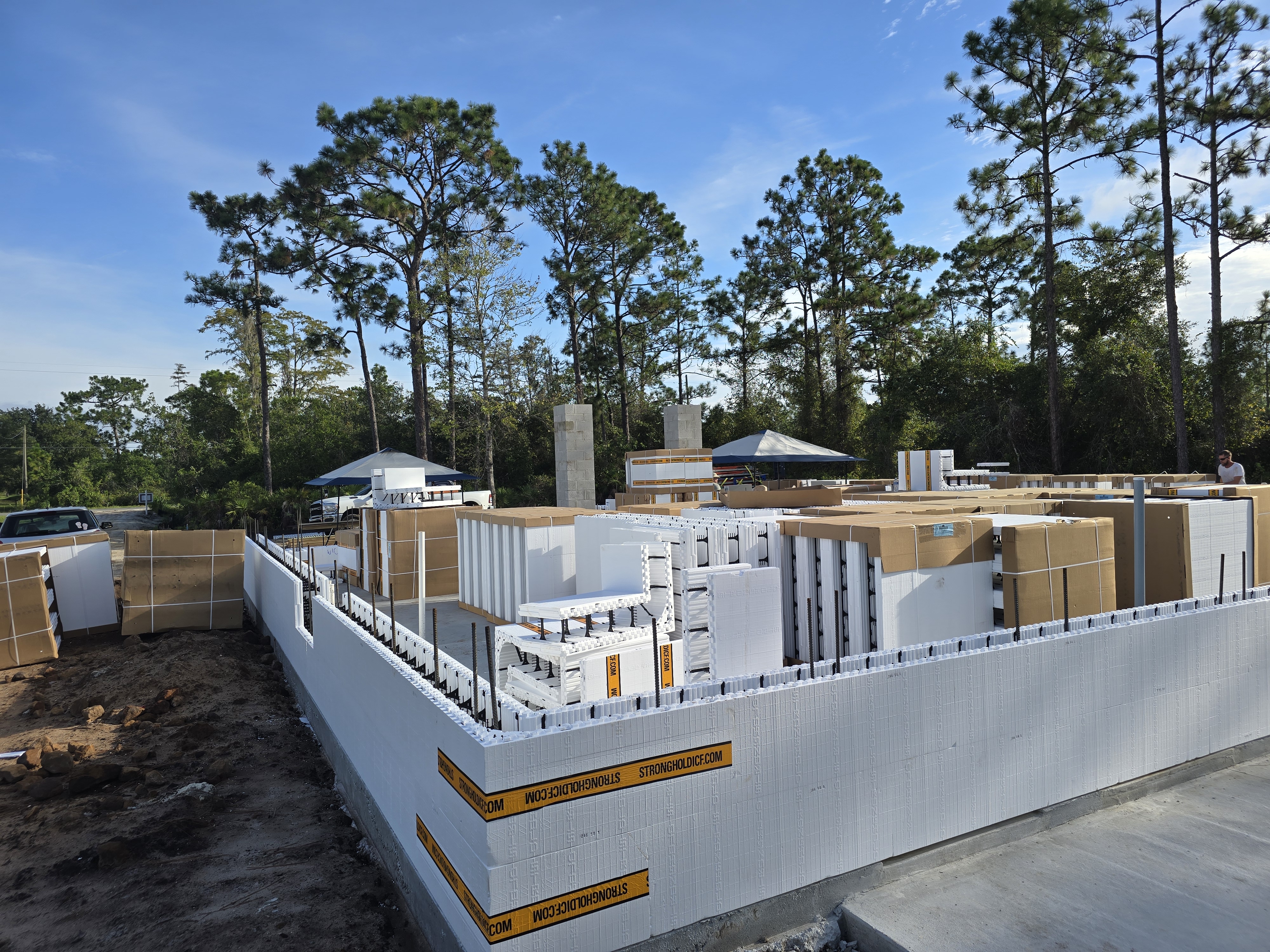 A construction site with walls made of insulated concrete forms (ICFs) is visible. The ICF blocks ar 