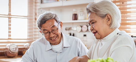 Elderly couple chopping vegetables together in their kitchen.