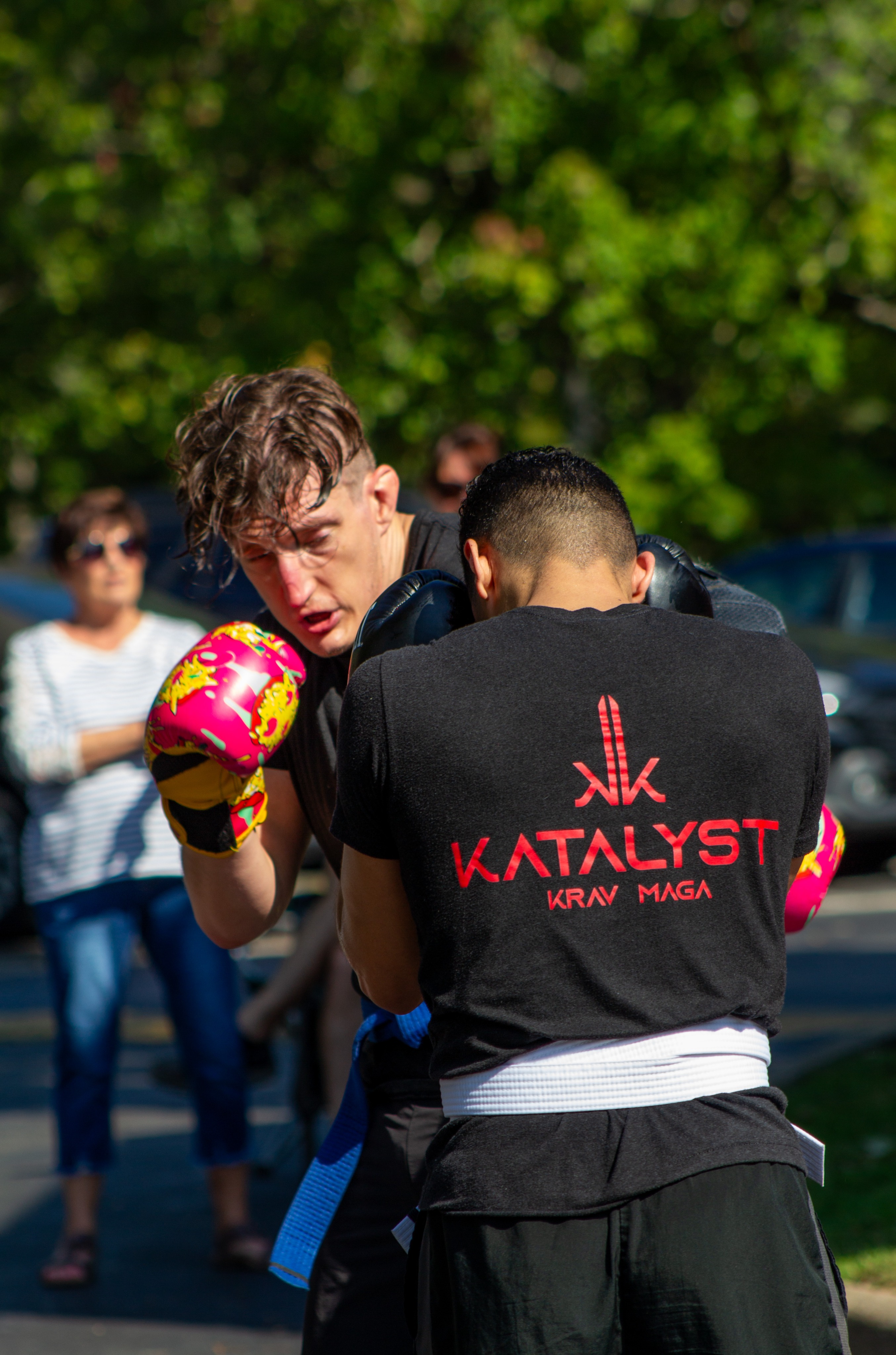 Two adult students sparring with boxing gloves during an outdoor training session.