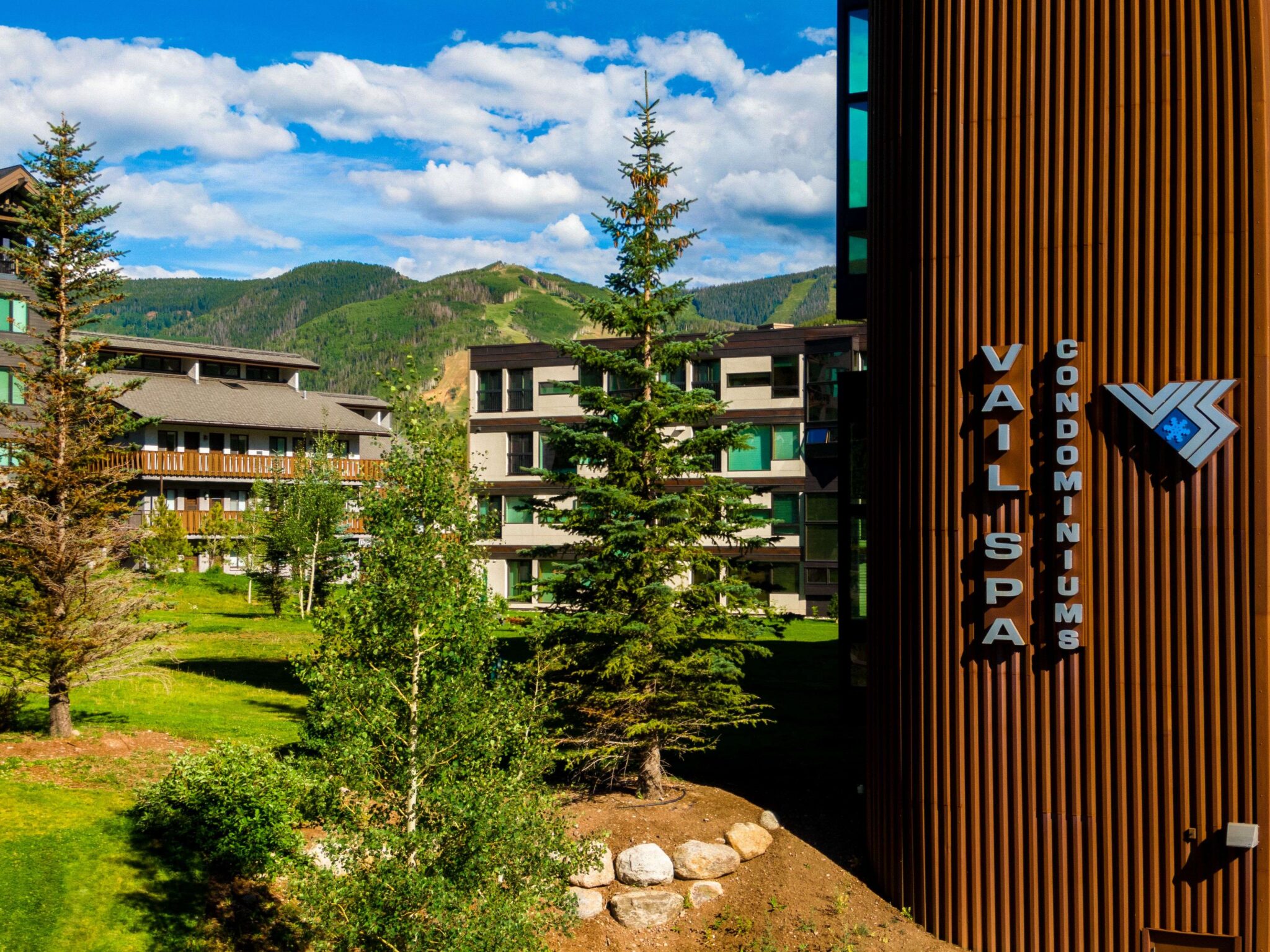 The exterior of Vail Spa Condominiums during the summer, with mountains in the background 