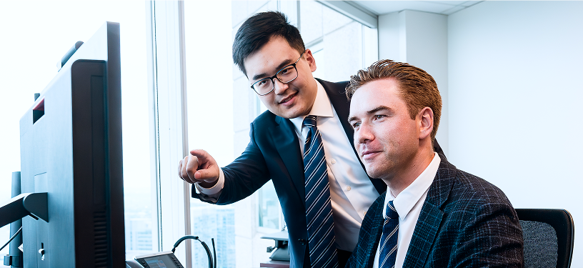 Two members of the Rae Family Wealth team looking at a monitor.